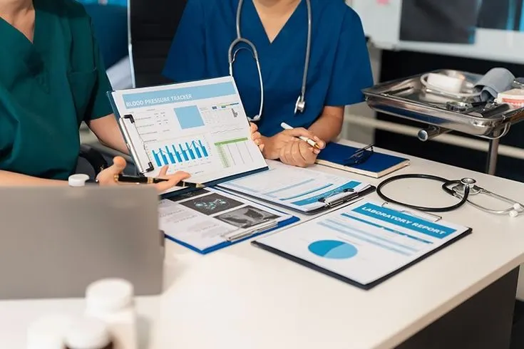 Healthcare professionals in scrubs reviewing medical analytics charts and laboratory reports for internal medicine medical billing services.