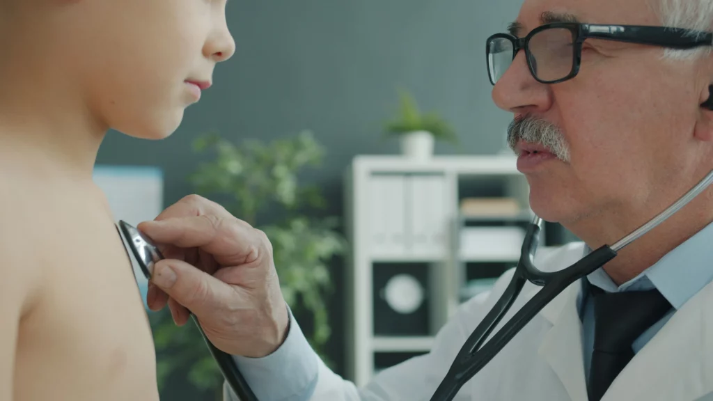 Family medicine doctor examining child patient with stethoscope for billing services